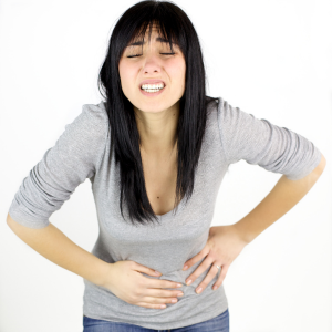 Mujer con las manos en la barriga, mostrando signos de dolor y malestar digestivo.